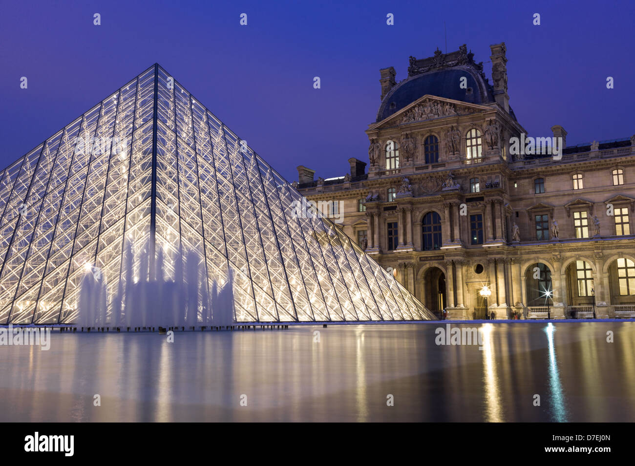 Museo del Louvre y la pirámide por la noche en París. Foto de stock
