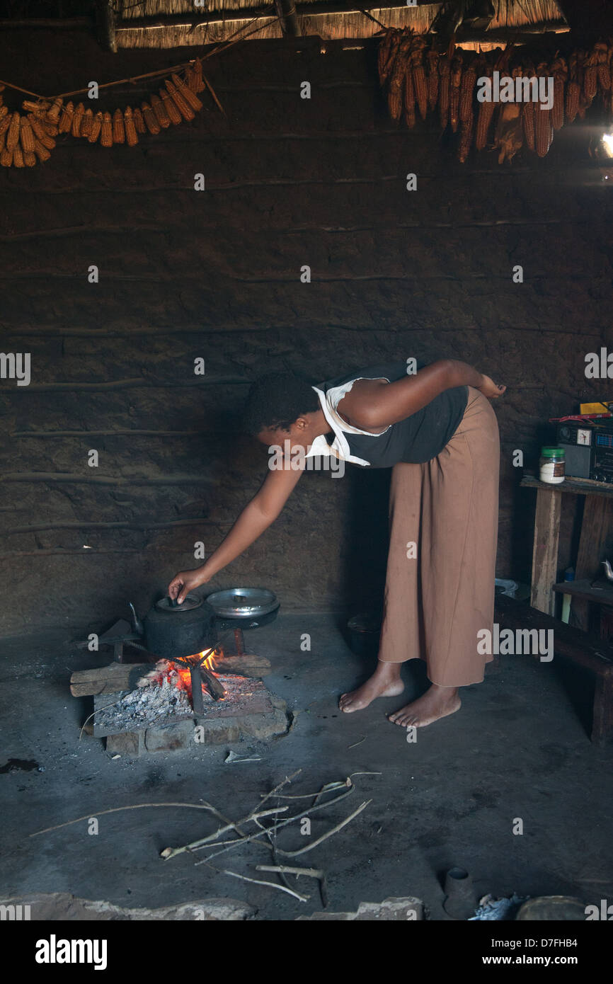 Señora africana ajustar tetera en el fuego Foto de stock