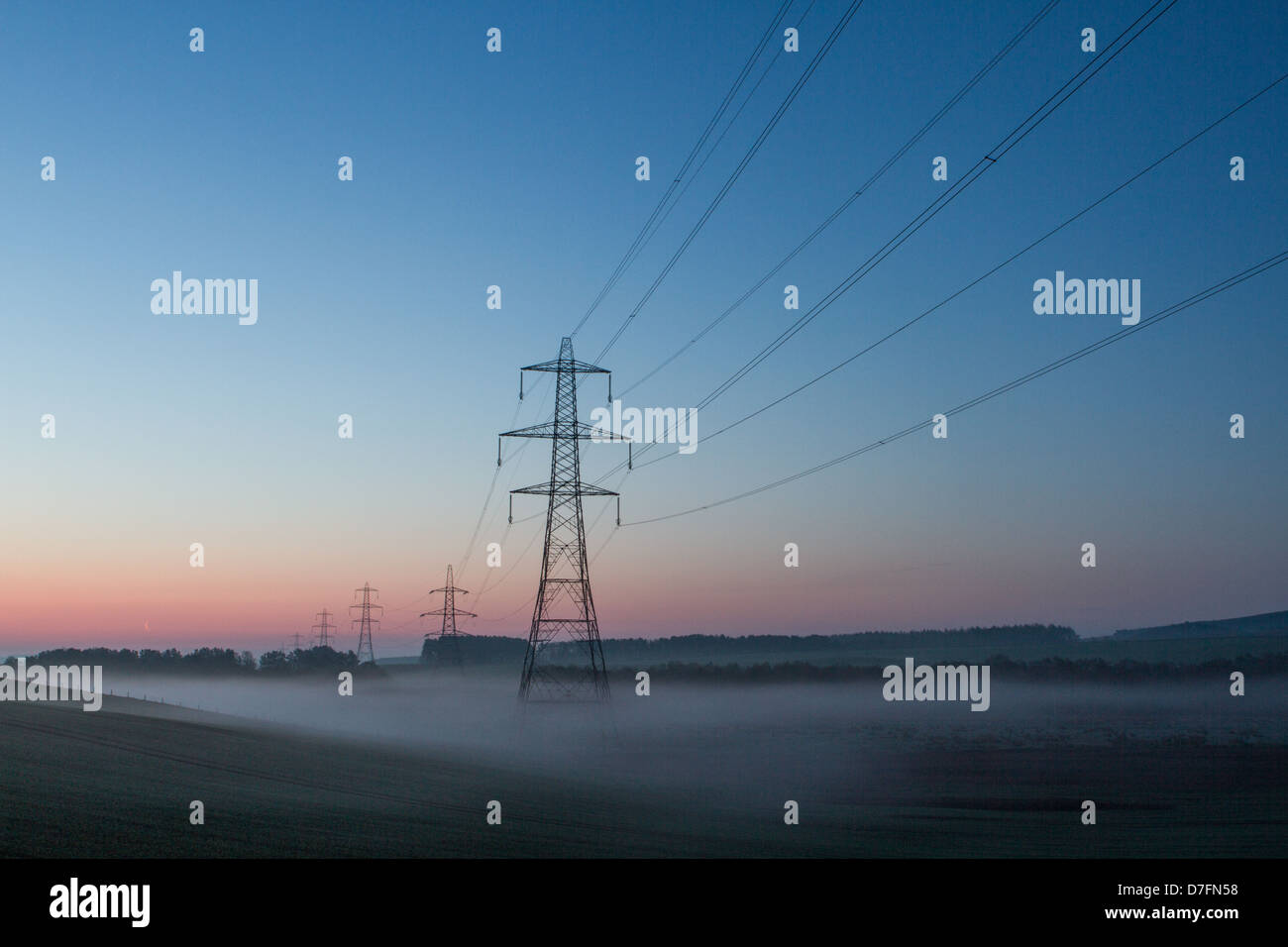 Los postes de la electricidad visto al amanecer en la frontera escocesa Foto de stock