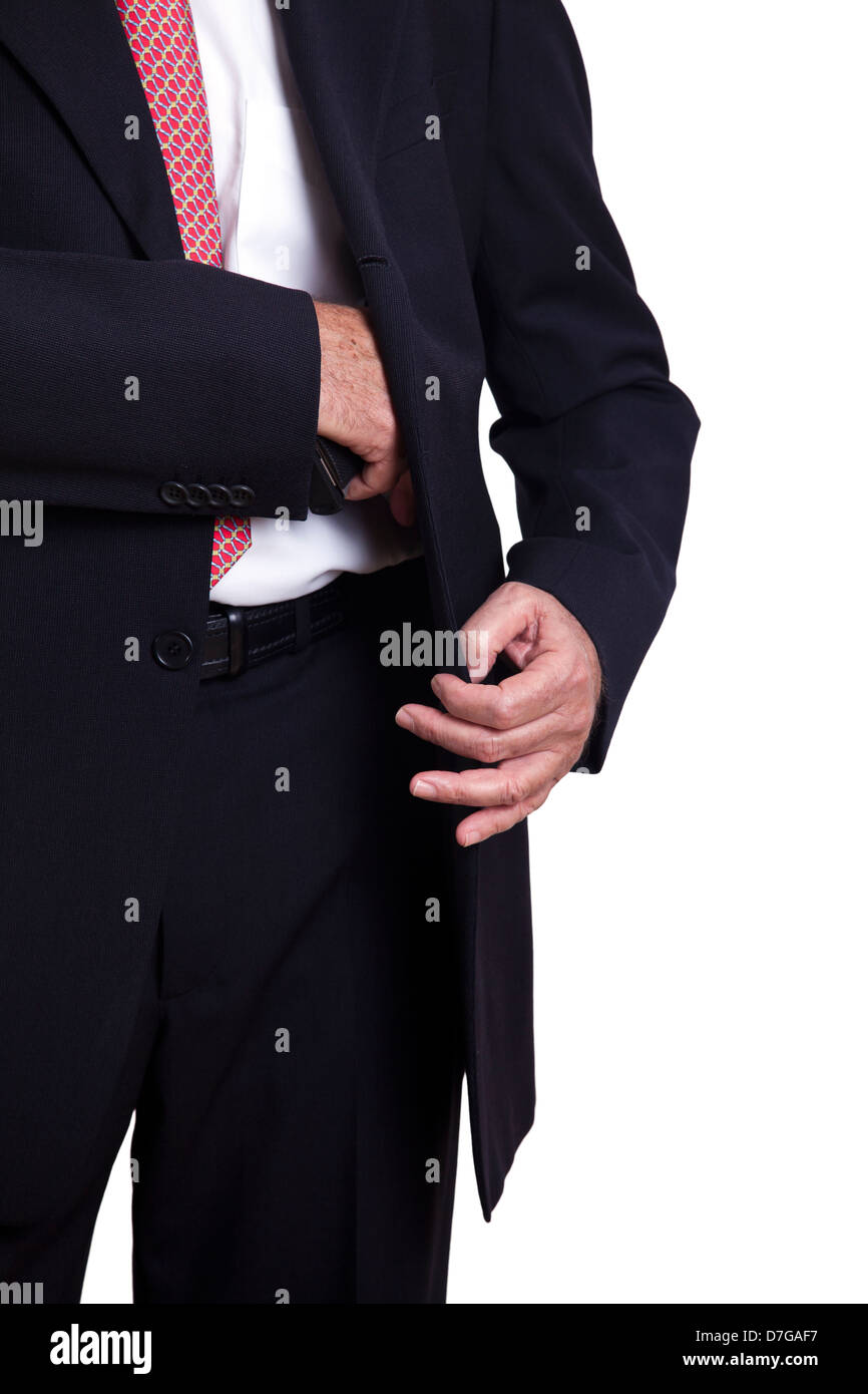 Un adulto vistiendo un traje tirando una pistola de 9mm fuera de su funda debajo de la chaqueta. Aislado sobre fondo blanco. Foto de stock