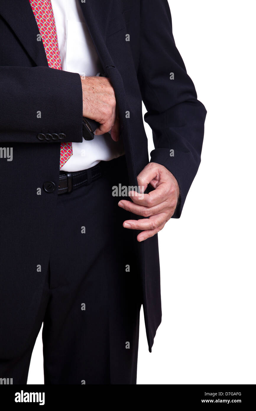 Un adulto vistiendo un traje tirando una pistola de 9mm fuera de su funda debajo de la chaqueta. Aislado sobre fondo blanco. Foto de stock