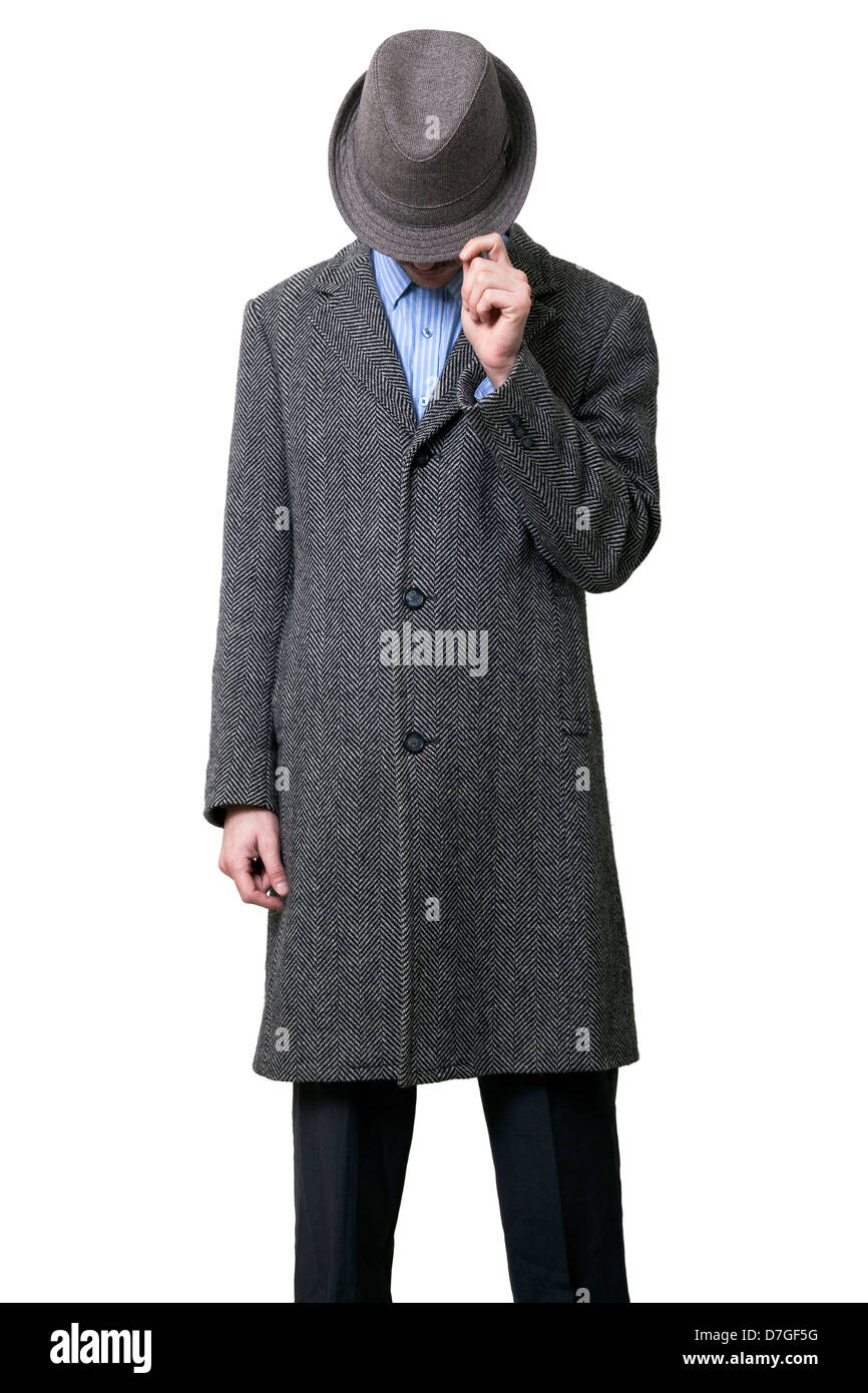 Un macho adulto joven vistiendo abrigo gris sombrero gris que está ocultando sus ojos. Él está sosteniendo hat su mano izquierda como si para ocultar Foto de stock