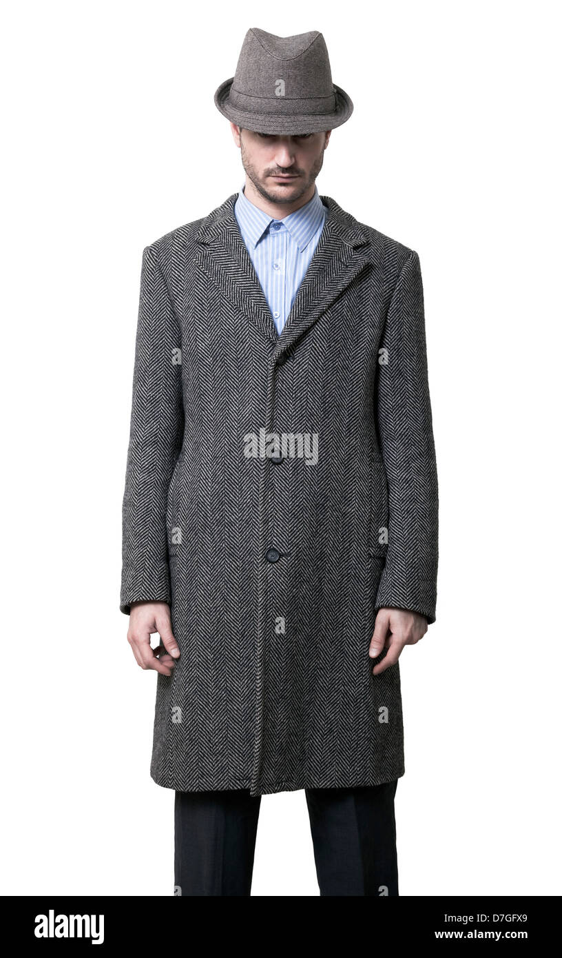 Una persona vestida con un abrigo gris y un sombrero gris que está ocultando sus ojos. Los brazos cruzados. Aislado sobre fondo blanco. Foto de stock