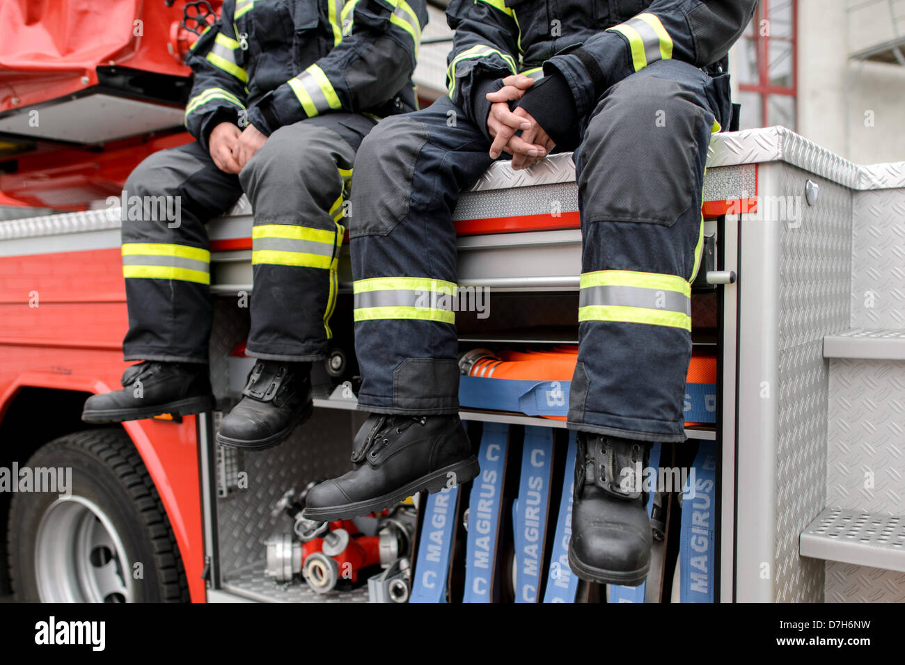 Dos bomberos sentarse en un camión de bomberos. Foto: Robert Schlesinger Foto de stock