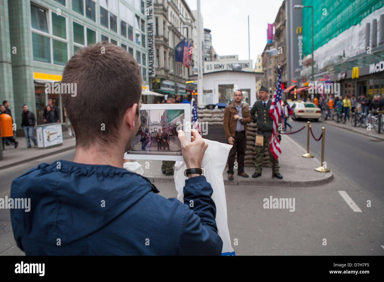 Los jóvenes turistas tomando fotografías con un Ipad en el Checkpoint Charly Foto de stock