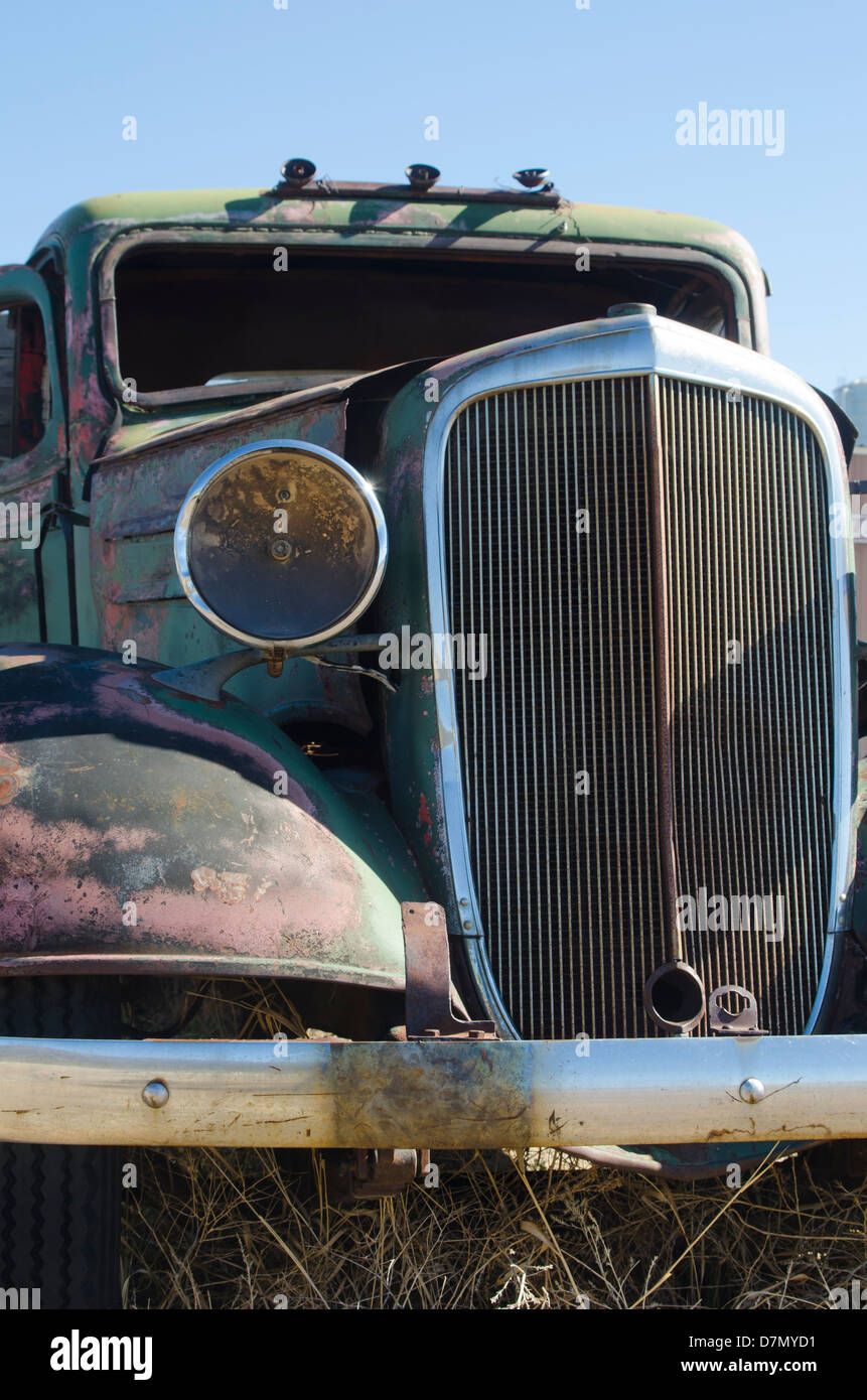 Un viejo camión de antigüedades se oxida lentamente en un campo de montaña, rejilla de faro y mostrando signos de un mejor día. días. Foto de stock