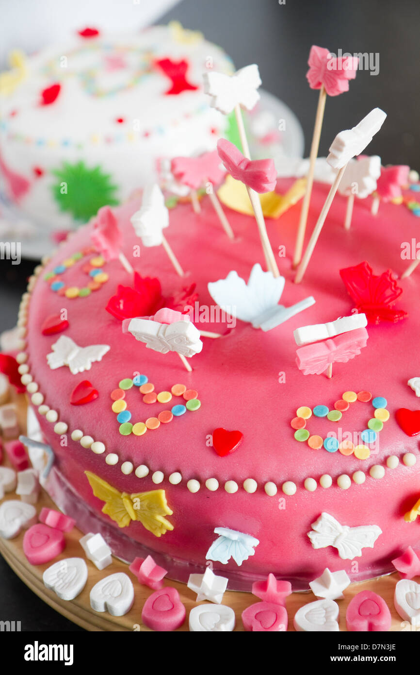 Decorados coloridos pasteles de mazapán blanco y rosa para una fiesta de cumpleaños en el aparador de cocina - Cerrar con poca dof Foto de stock