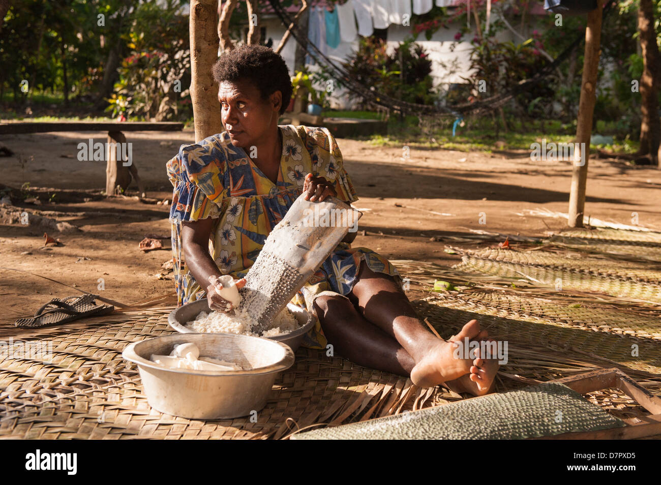 Vida de pueblo tradicional con una mujer sentada en la alfombrilla rallar mandioca. Bahía de Banam Malekula, Vanuatu. Foto de stock