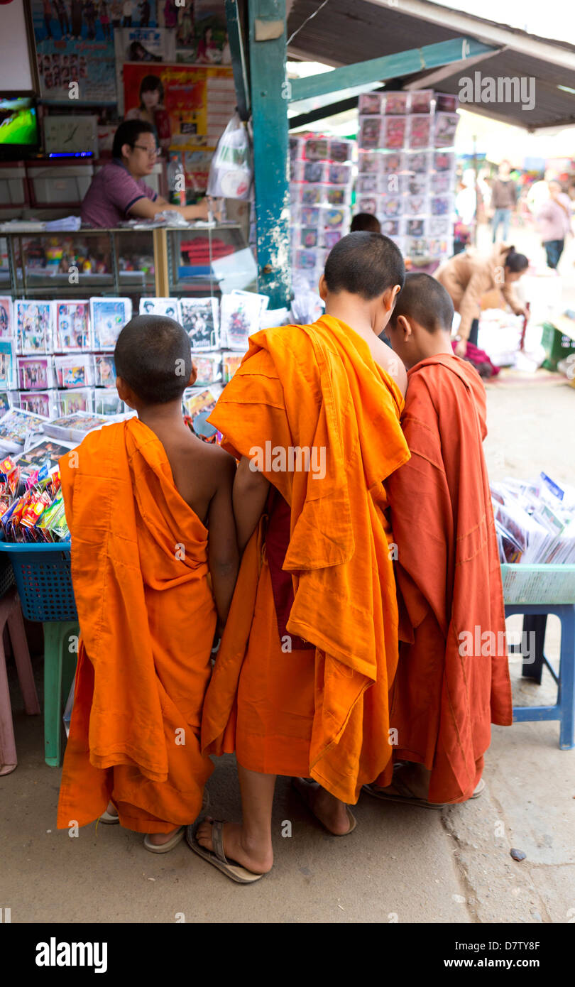 Tres monjes novicios comprando comics en el mercado de la ciudad, Kengtung (Kyaingtong), el Estado de Shan, Birmania Foto de stock