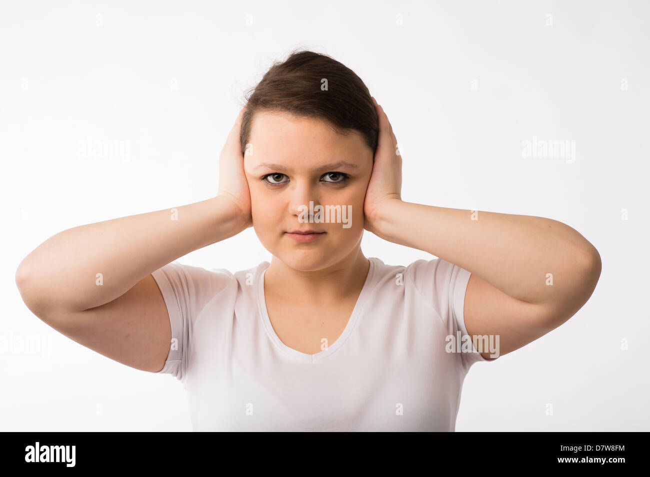 Hear No Evil: Una joven morenita adolescente chica caucásica sosteniendo sus manos sobre las orejas. Foto de stock