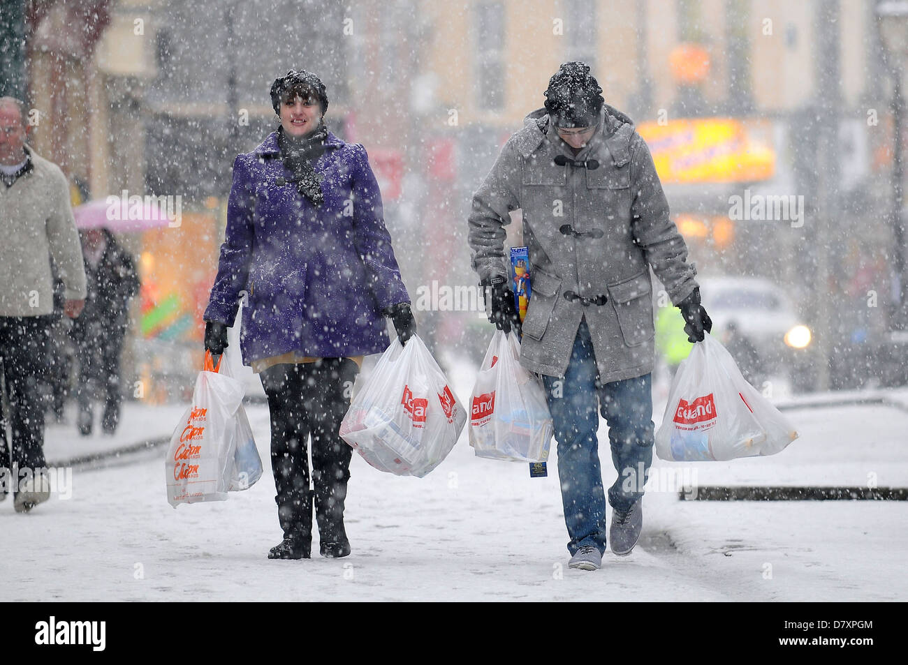 Una joven pareja realizar compras a través de una ventisca de nieve pesada en Pontypridd, Gales. Foto de stock