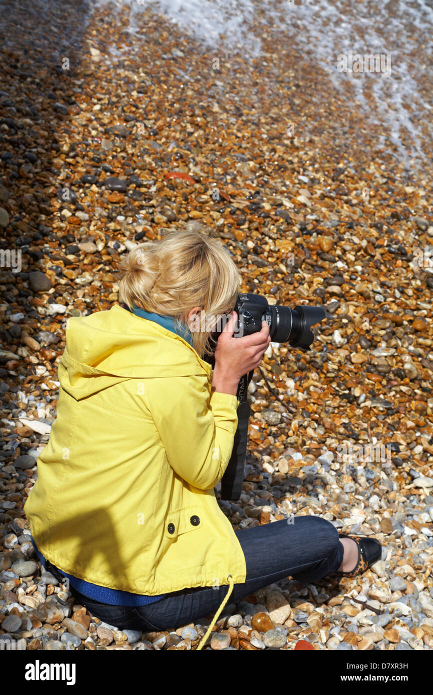 La mujer se sentó en la playa tomando fotos en la Isla de Wight en mayo Foto de stock