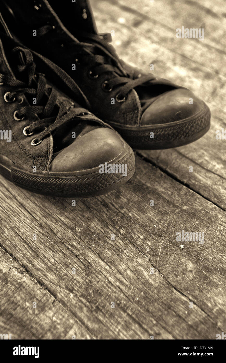 Zapatillas viejas. Viejo Negro zapatillas sobre el piso de madera, imágenes  monocromáticas Fotografía de stock - Alamy