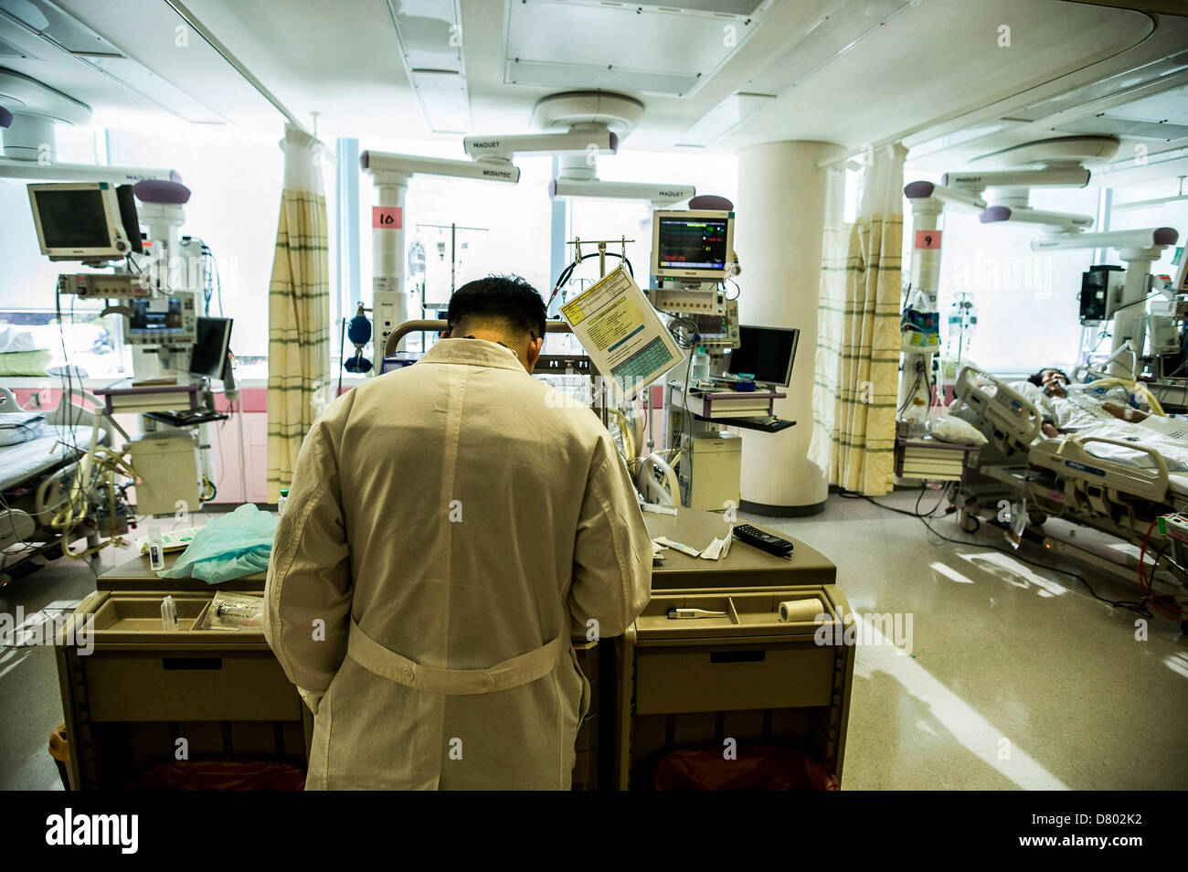 Un médico examina los registros de paciente en la unidad de cuidados intensivos, Samsung Medical Center, Corea. Foto de stock