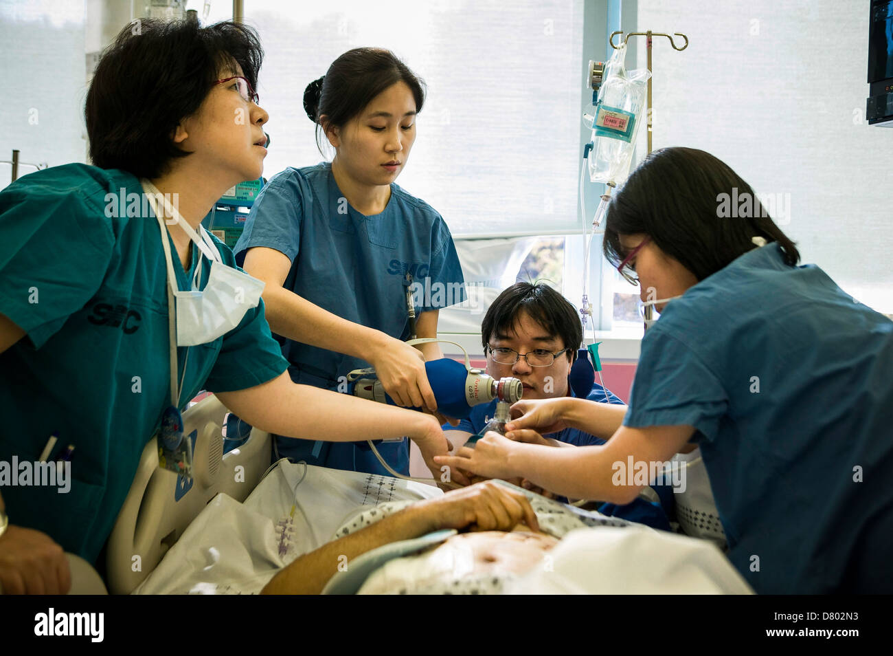 Personal médico usar un tanque de oxígeno para ayudar a reavivar la paciente que ha sido bajo anestesia en la unidad de cuidados intensivos Foto de stock