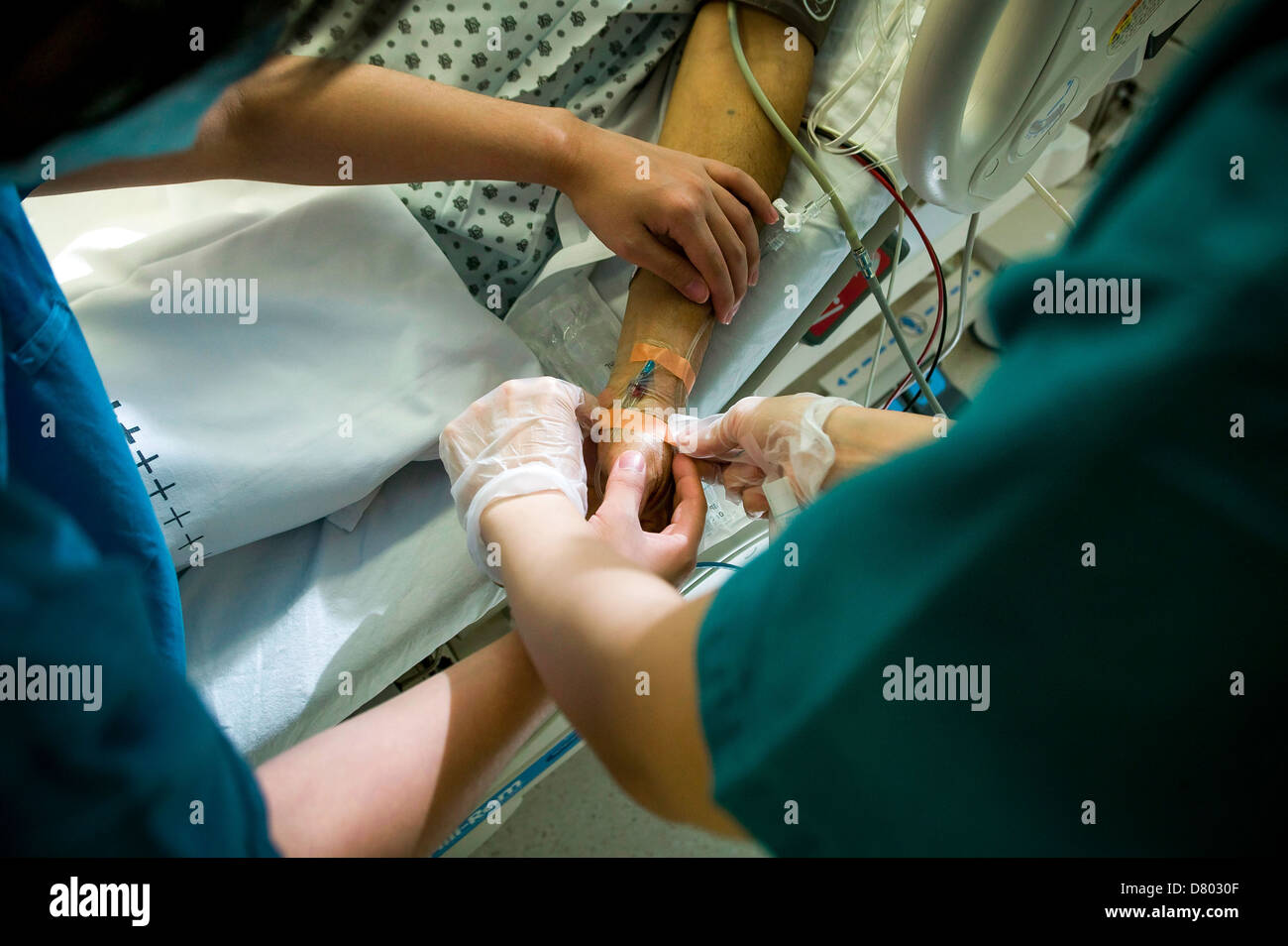 Un paciente tiene un gotero intravenoso insertado en el brazo, en una unidad de cuidados intensivos. Foto de stock