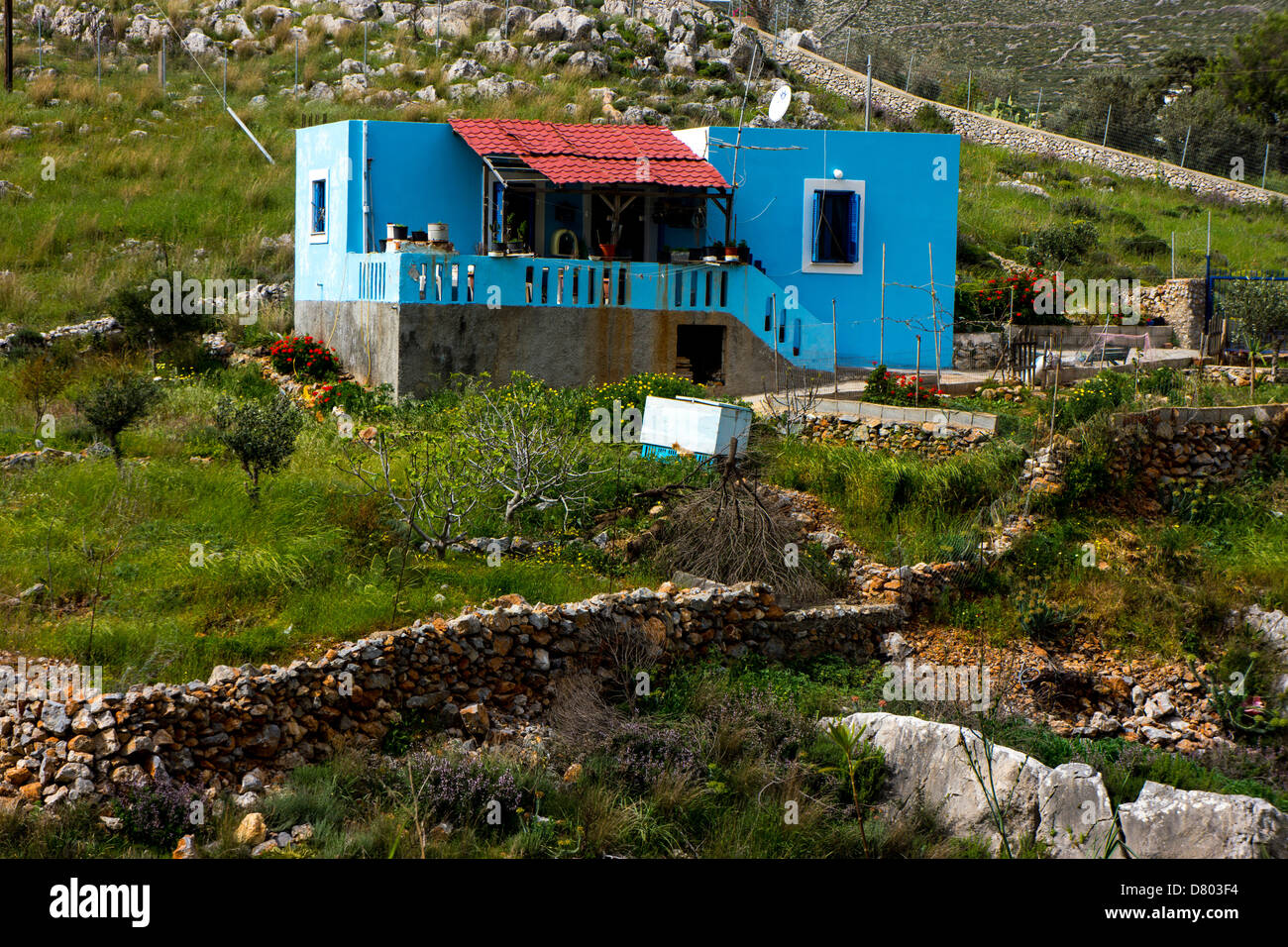 Griego azul pequeña casa rodeada por campos verdes Foto de stock
