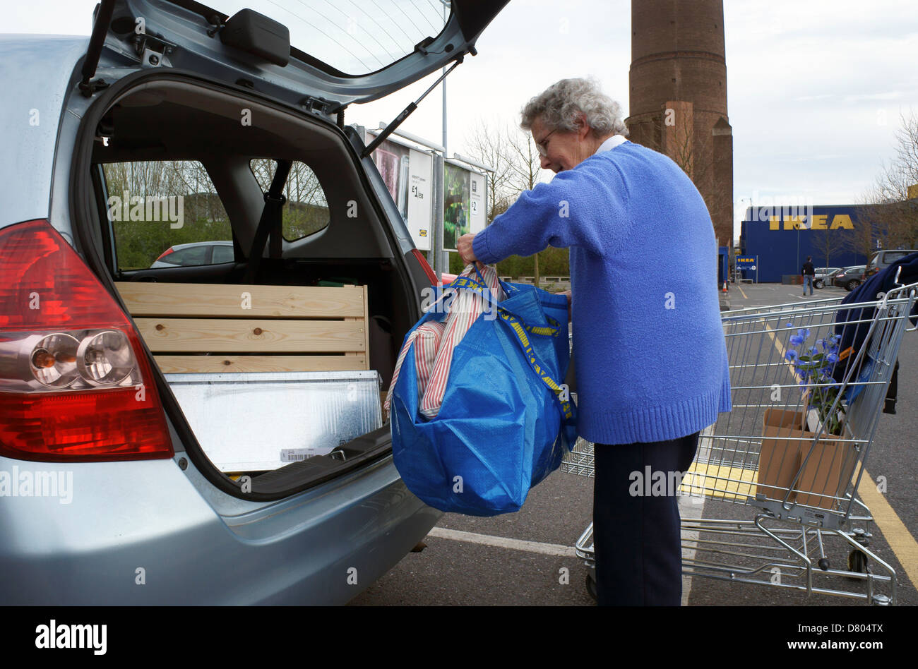 Pensionista femenino senior citizen cargando las compras en IKEA Croydon en la parte trasera de un coche Foto de stock
