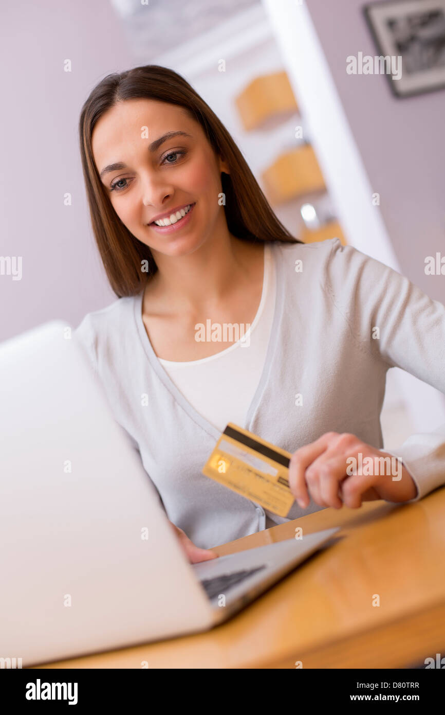 Mujer sosteniendo una tarjeta de cargo y las compras de la web en el ordenador portátil Foto de stock