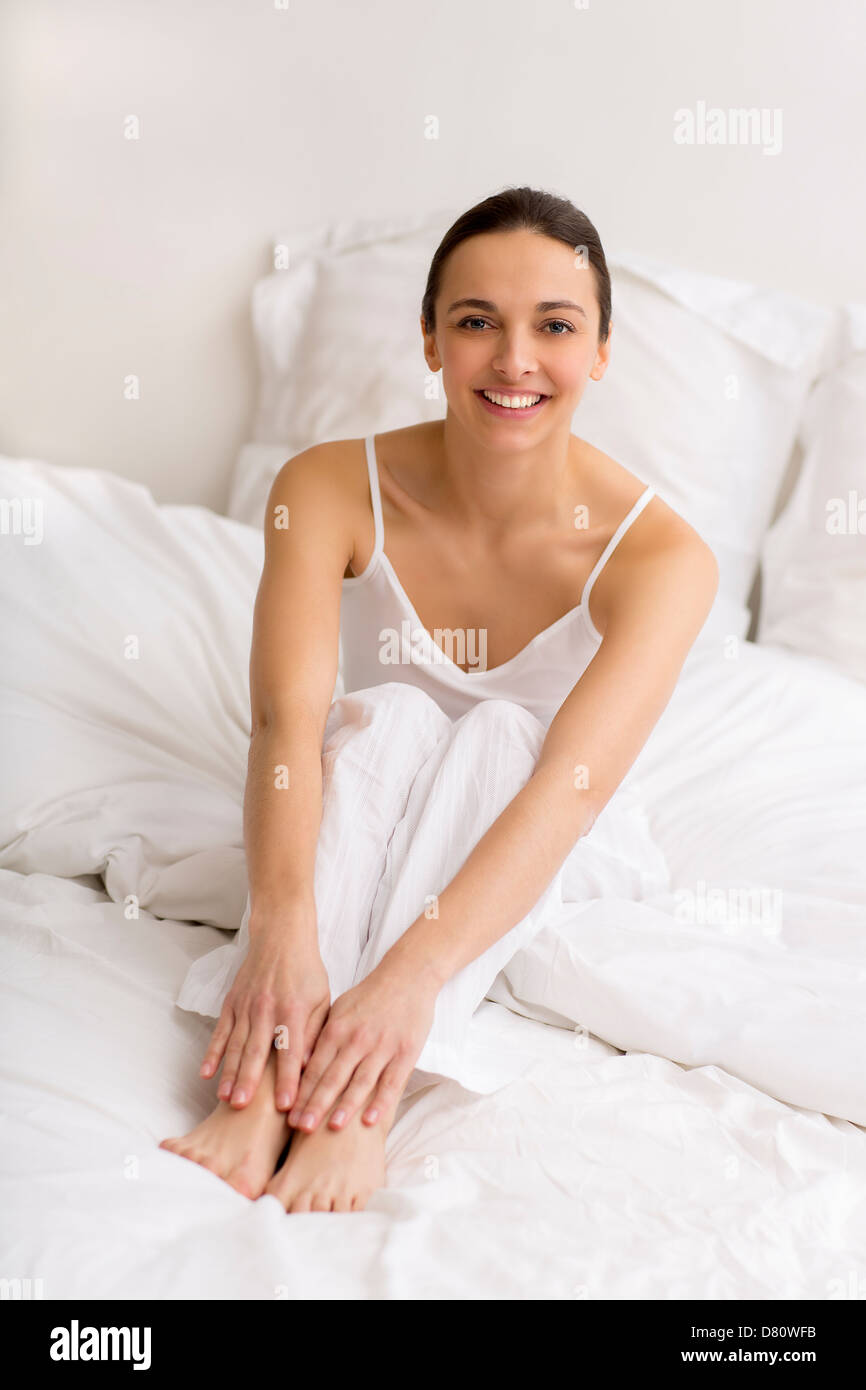 Retrato de mujer joven sonriente en la cama en casa Foto de stock