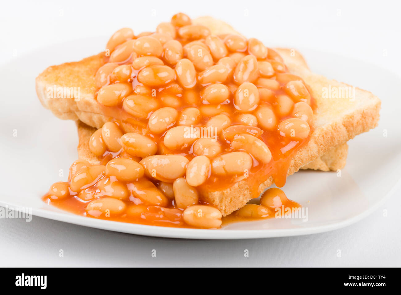 Frijoles en las tostadas, rebanadas de pan blanco tostado, untado con mantequilla y cubierto con baked beans. Simple desayuno Británico. Foto de stock