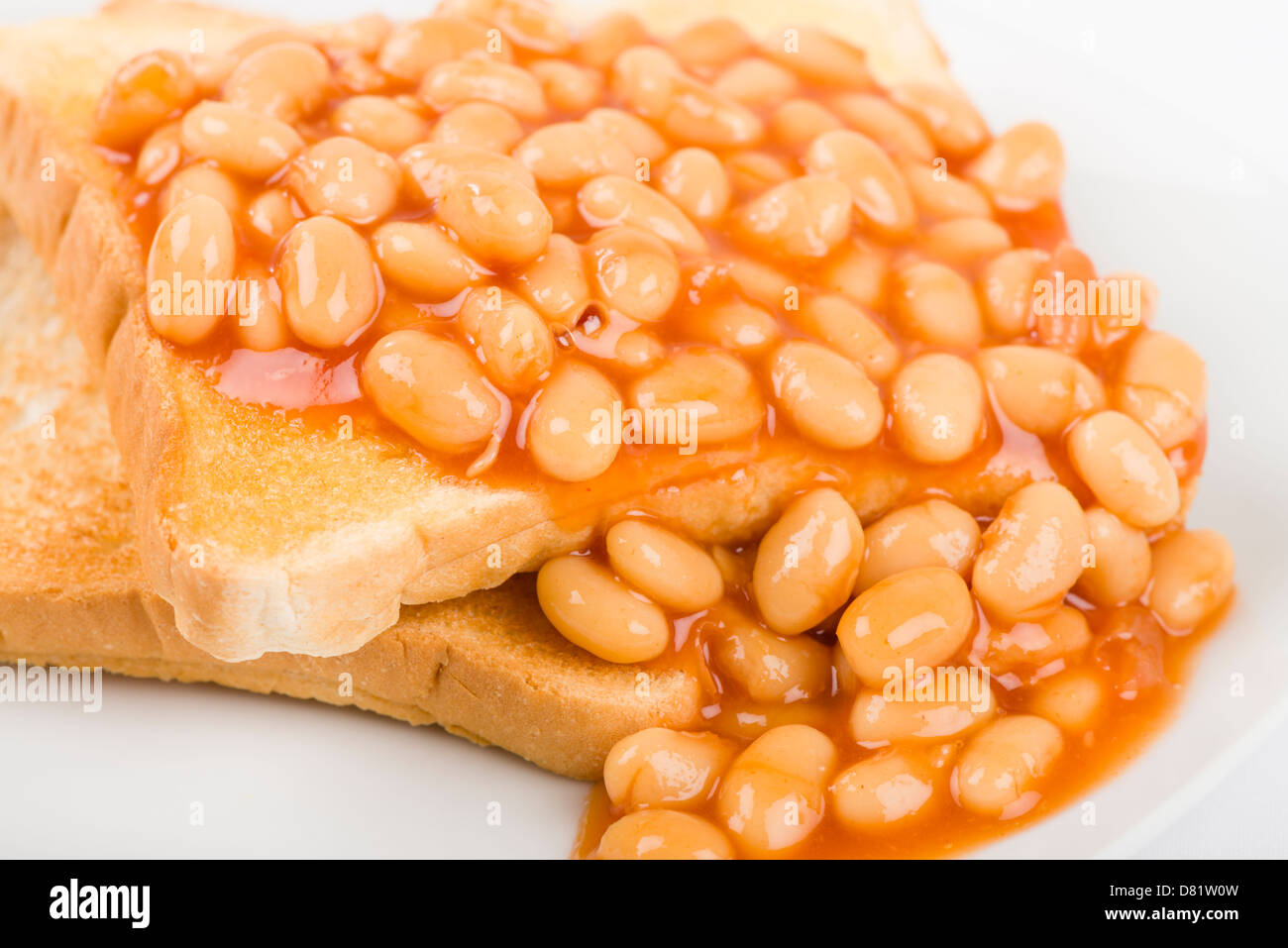 Frijoles en las tostadas, rebanadas de pan blanco tostado, untado con mantequilla y cubierto con baked beans. Simple desayuno Británico. Foto de stock