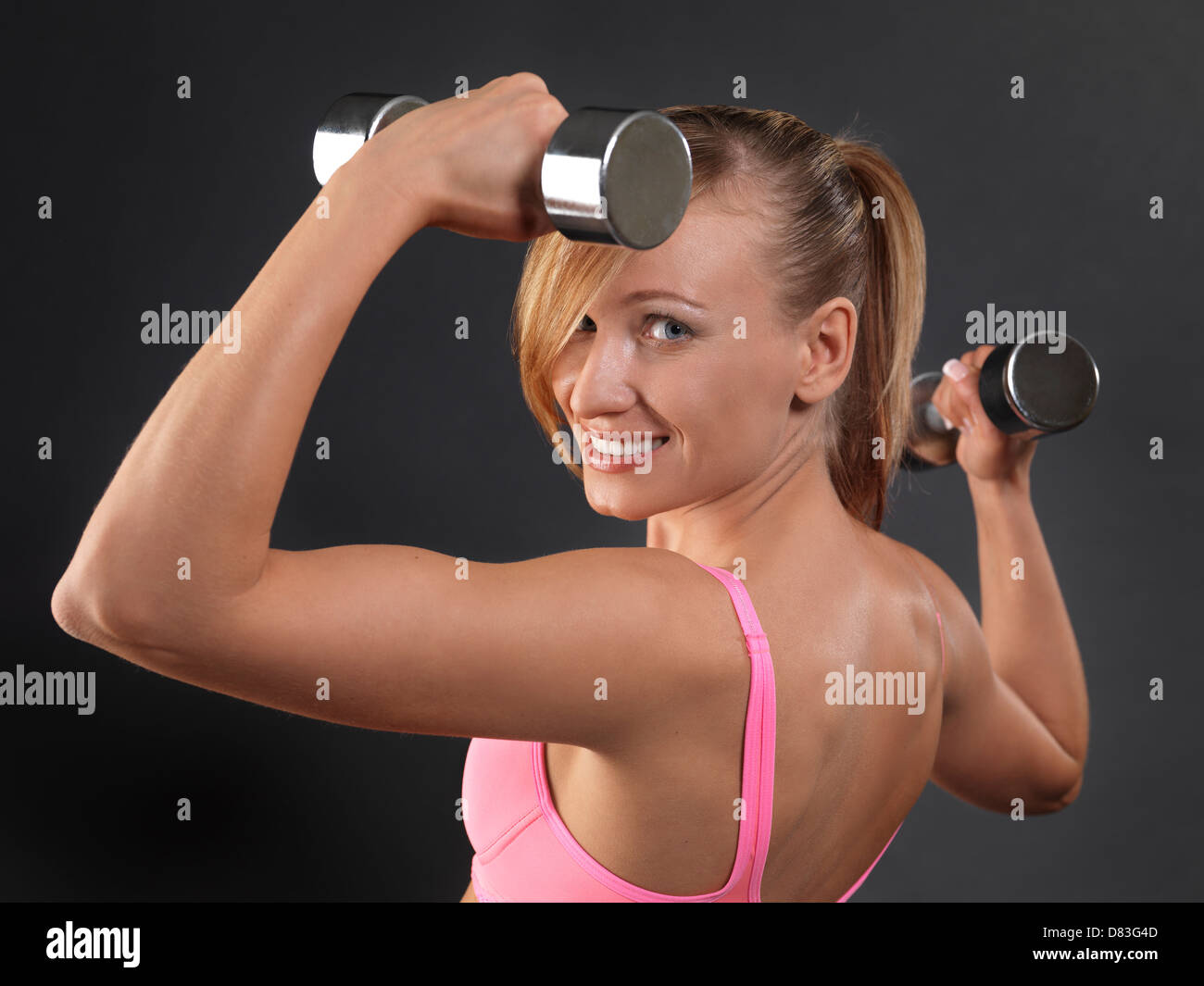 Retrato de un joven sonriente mujer fitness el ejercicio con pesas Foto de stock