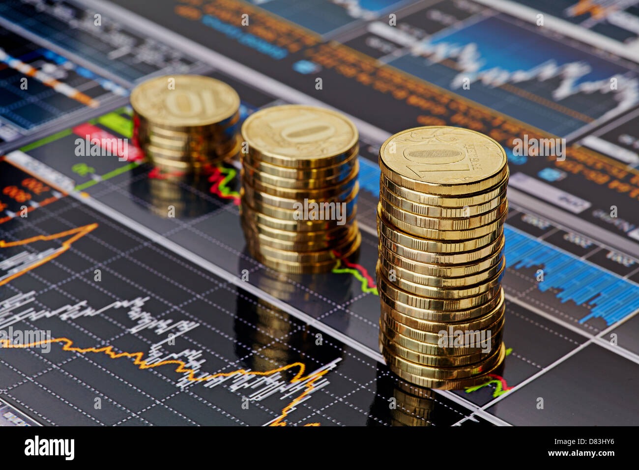 Subida apila monedas,en los gráficos de cotizaciones financieras como fondo. Enfoque selectivo Foto de stock