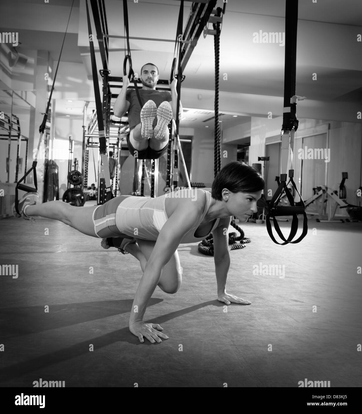 Crossfit TRX fitness ejercicios de entrenamiento en el gimnasio mujer push-up y anillos dip hombre entrenamiento Foto de stock