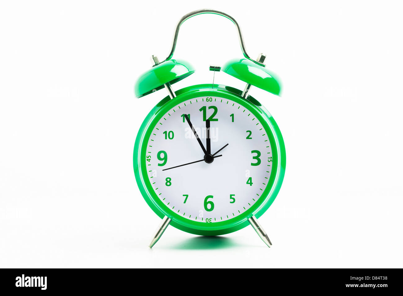 Imagen de un reloj despertador retro verde sobre un fondo blanco con el reloj de 5 a 12 Foto de stock