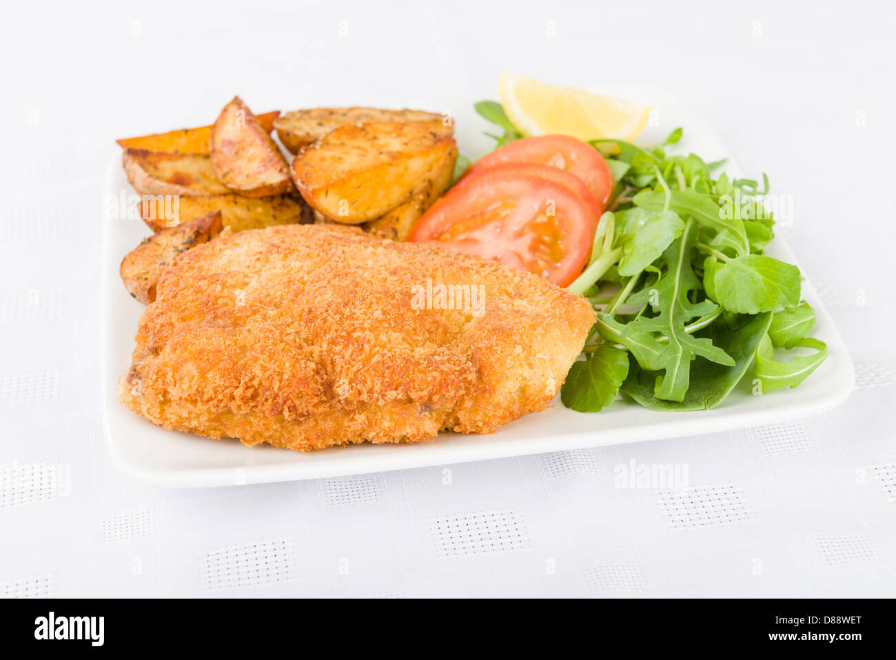 El Wiener Schnitzel (filete de ternera empanado y frito en mantequilla servido con ensalada, patatas y una rodaja de limón. Foto de stock