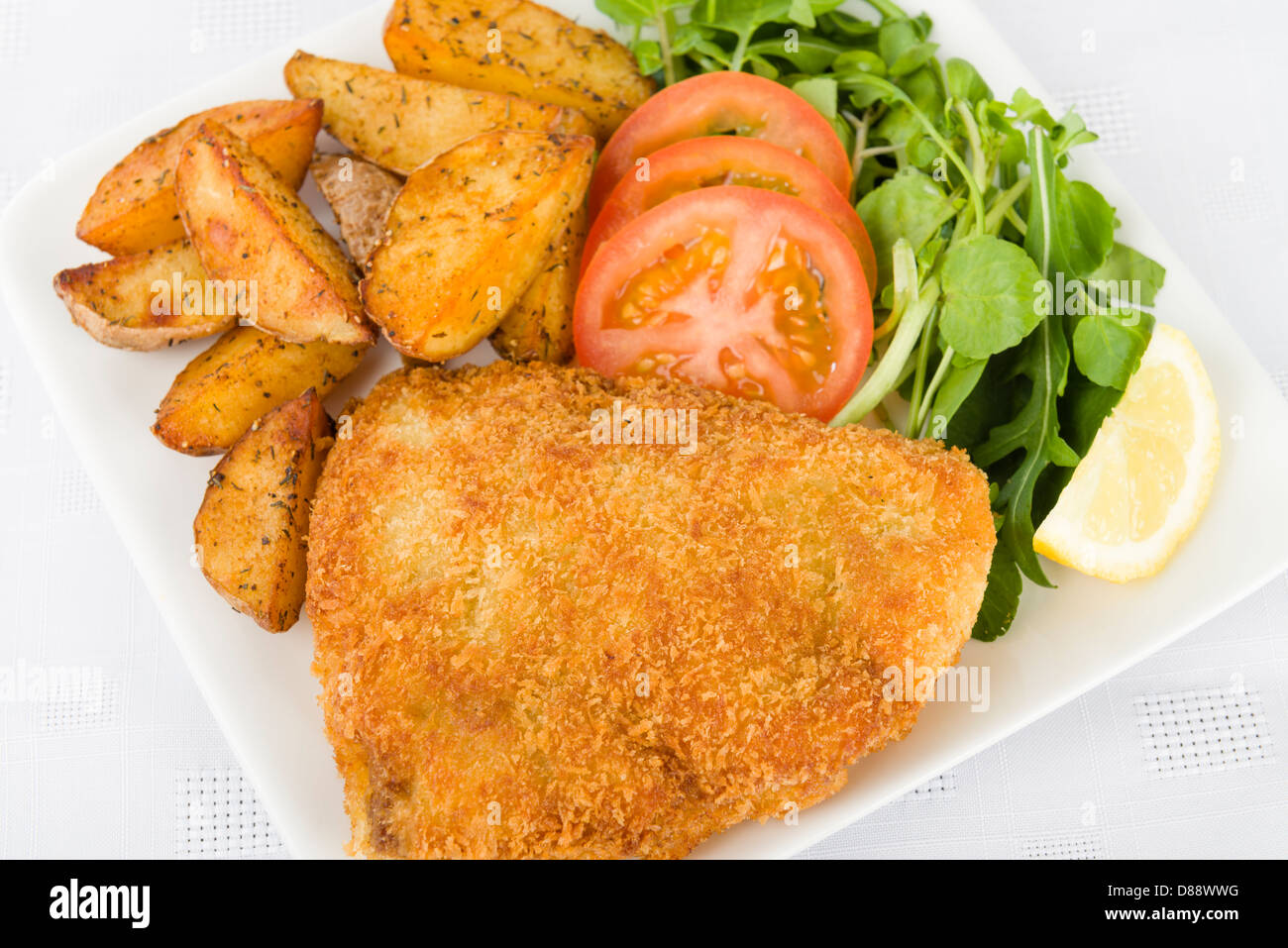 El Wiener Schnitzel (filete de ternera empanado y frito en mantequilla servido con ensalada, patatas y una rodaja de limón. Foto de stock