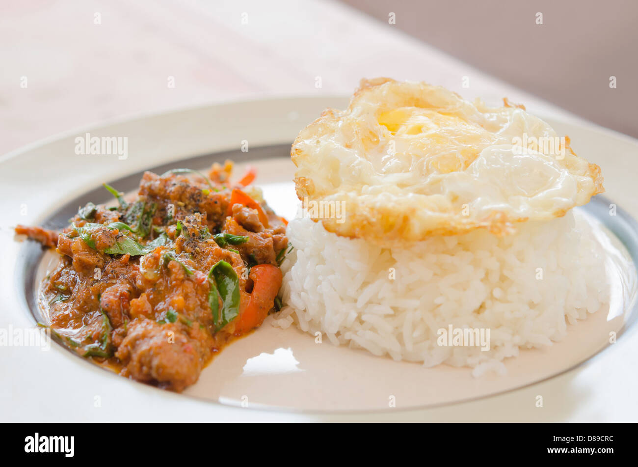 La comida asiática , huevo frito sobre arroz y carne de cerdo frita con ají y salsa de curry Foto de stock
