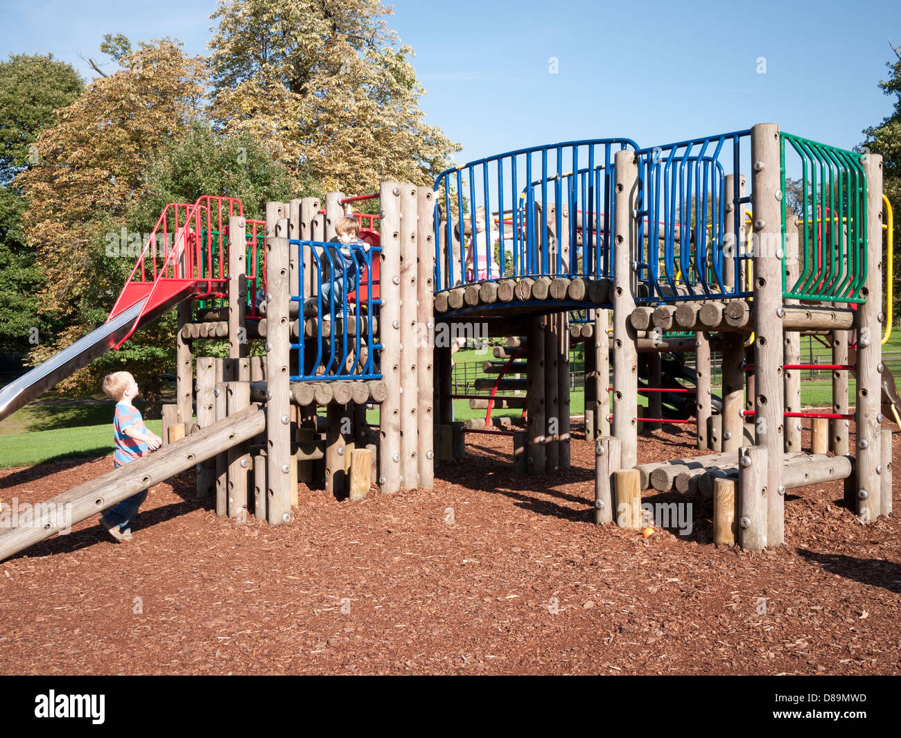 Niños jugando en un marco de escalada y deslizar en el área de juego de Golders Hill Park, North West London Foto de stock