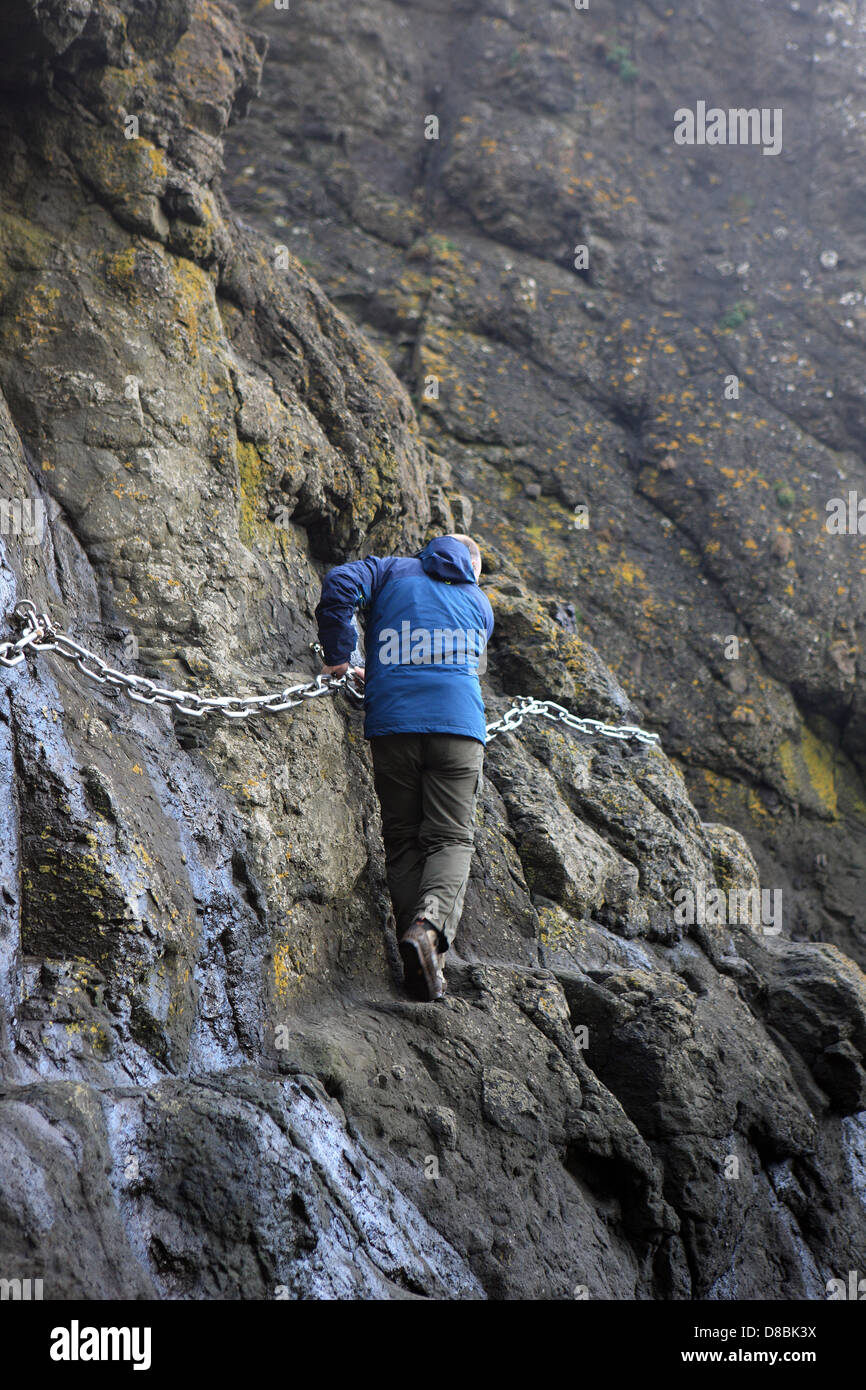 Elie Cadena Walk - hombre utilizando la cadena para ayudar a atravesar una cornisa del acantilado Foto de stock