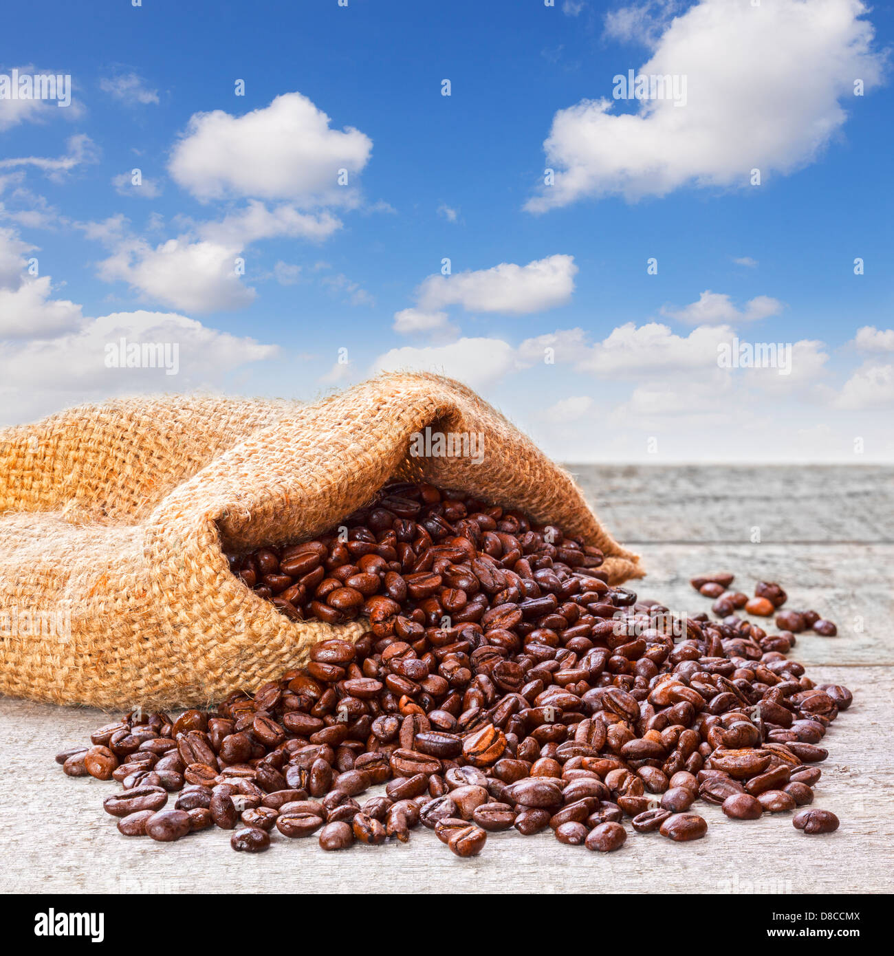 Los granos de café saliendo de saco y Blue Sky - granos de café tostado fresco saliendo de un saco de yute o arpillera... Foto de stock