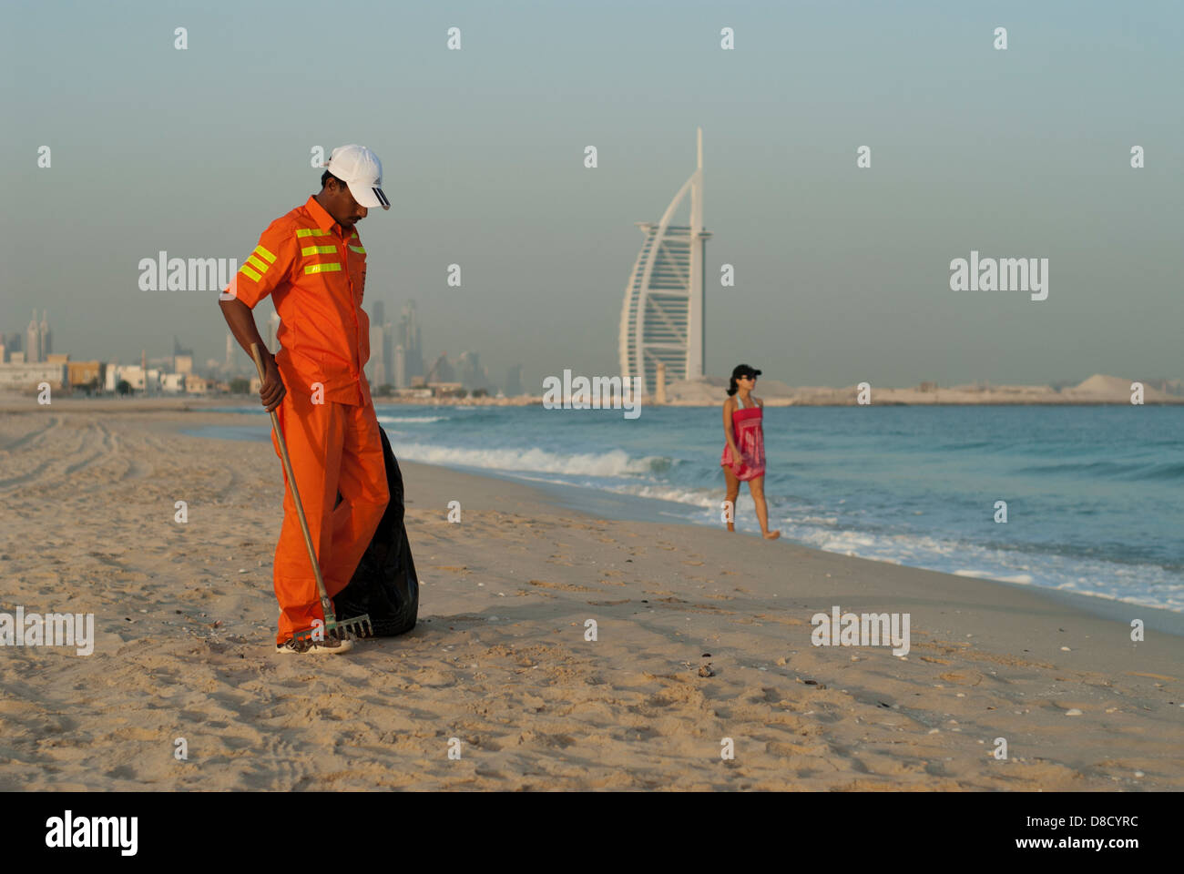 Trabajador migrante recogiendo basura en la playa de Dubai Foto de stock