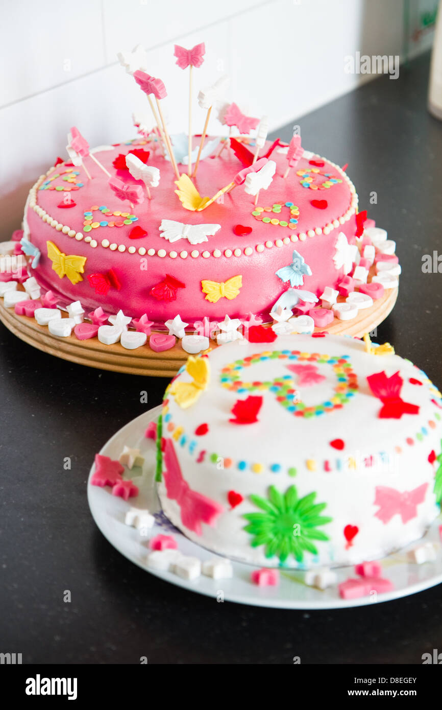 Deliciosos decorados coloridos pasteles de mazapán blanco y rosa para una fiesta de cumpleaños en el aparador de cocina Foto de stock