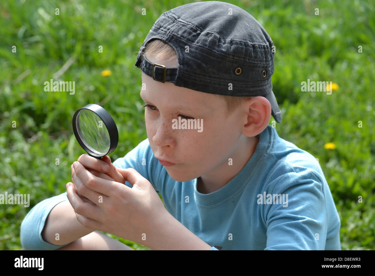 El adolescente observa a través de una lupa Foto de stock