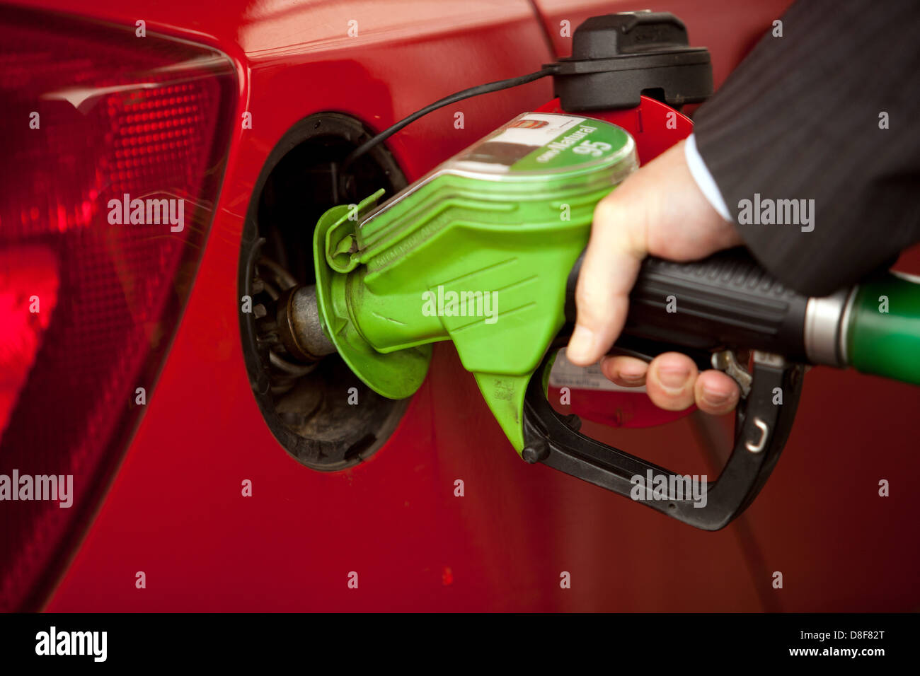 Hombre mano bombear la boquilla de gasolina y llena la gasolina en un coche aumentar el crecimiento de precios Foto de stock