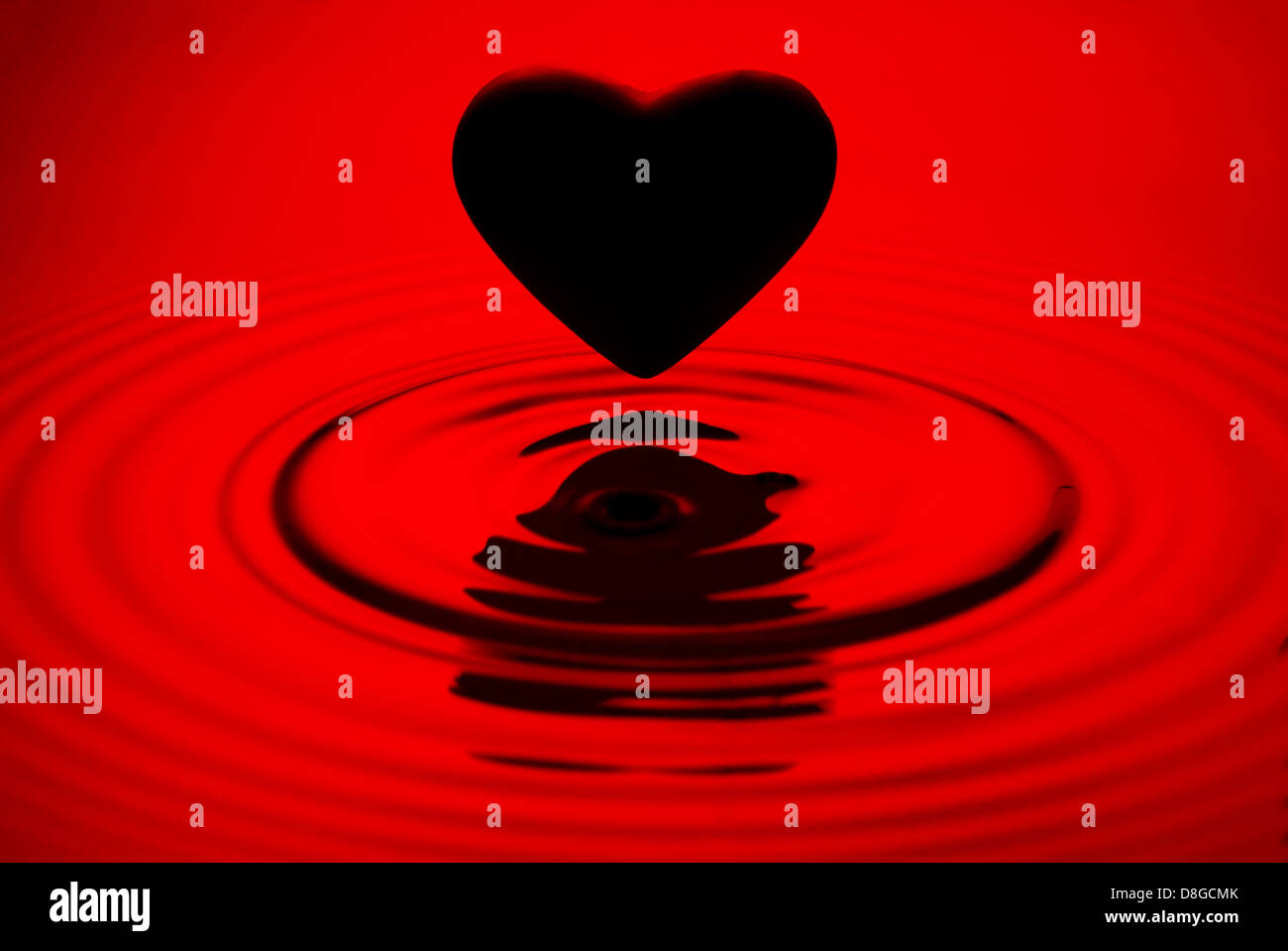 Corazón negro sobre rojo siluett ondulaciones del agua Foto de stock