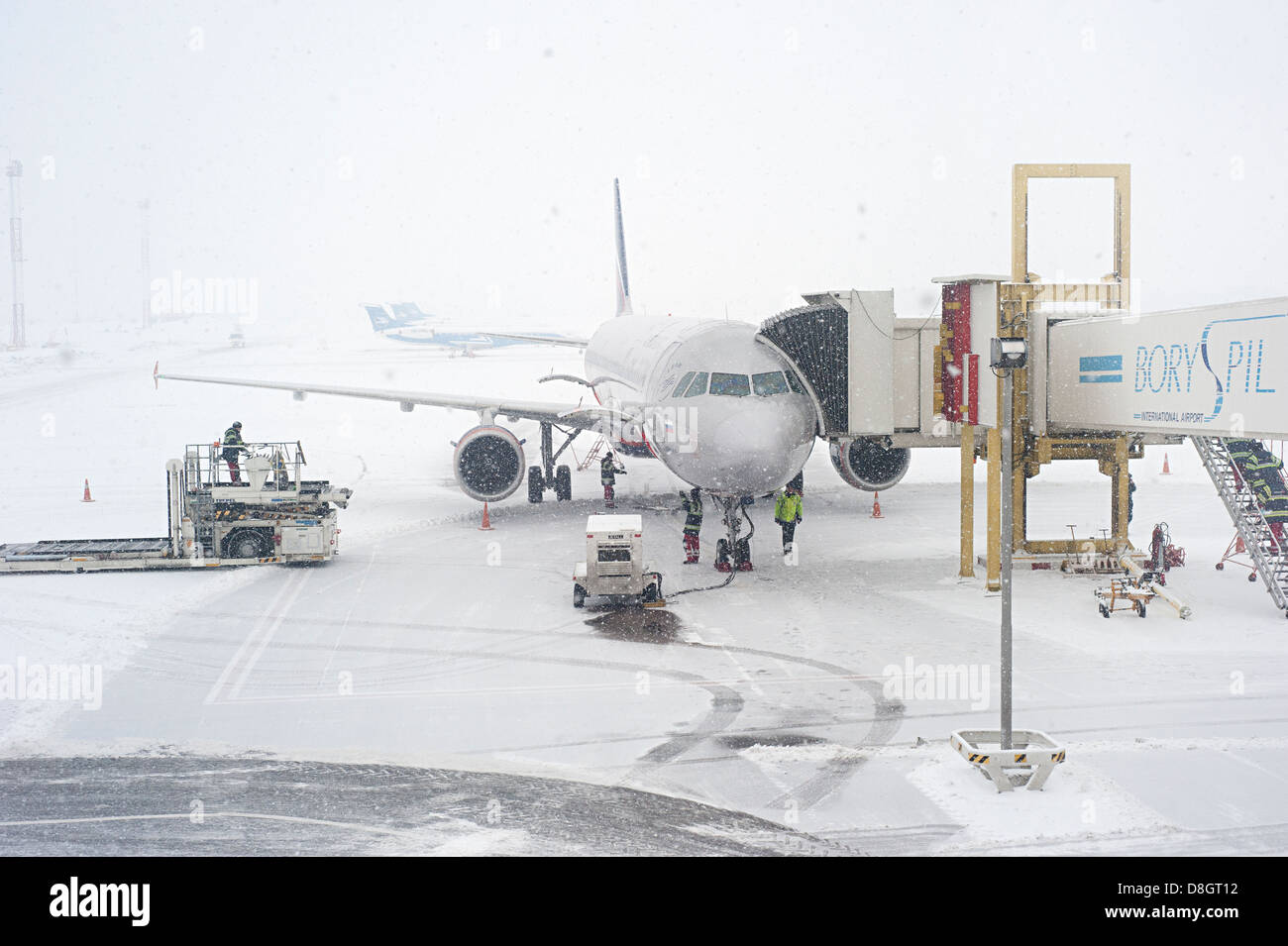 Los trabajadores preparando un avión para volar durante la nevada Foto de stock