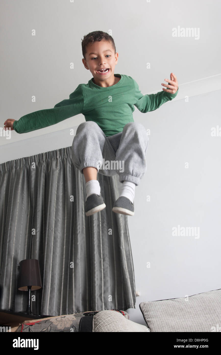 Niño hiperactivo saltando fuera de sofá Foto de stock