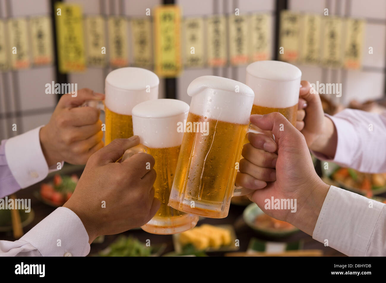 Cuatro personas brindando con cerveza en Izakaya Foto de stock