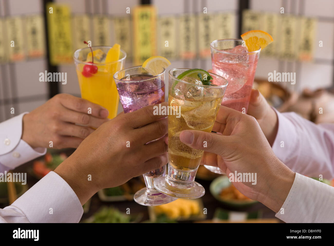 Cuatro personas brindando con varios cócteles en Izakaya Foto de stock