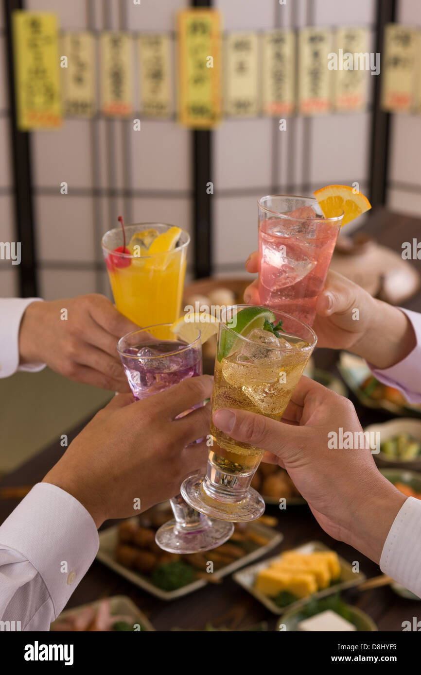Cuatro personas brindando con varios cócteles en Izakaya Foto de stock