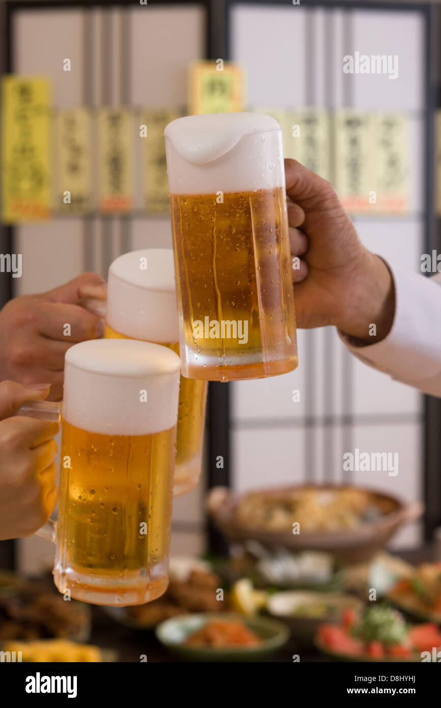 Tres personas brindando con cerveza en Izakaya Foto de stock