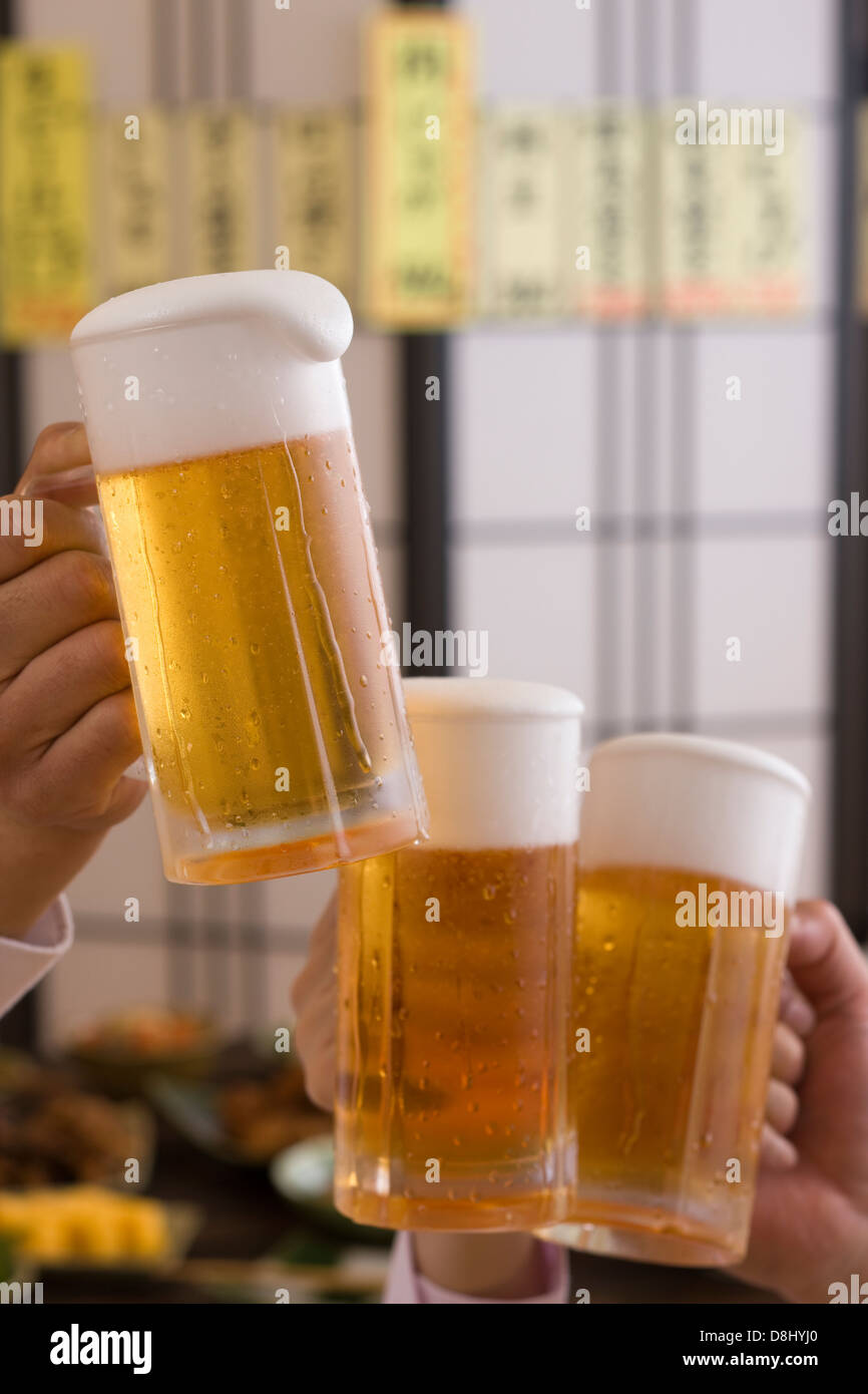 Tres personas brindando con cerveza en Izakaya Foto de stock