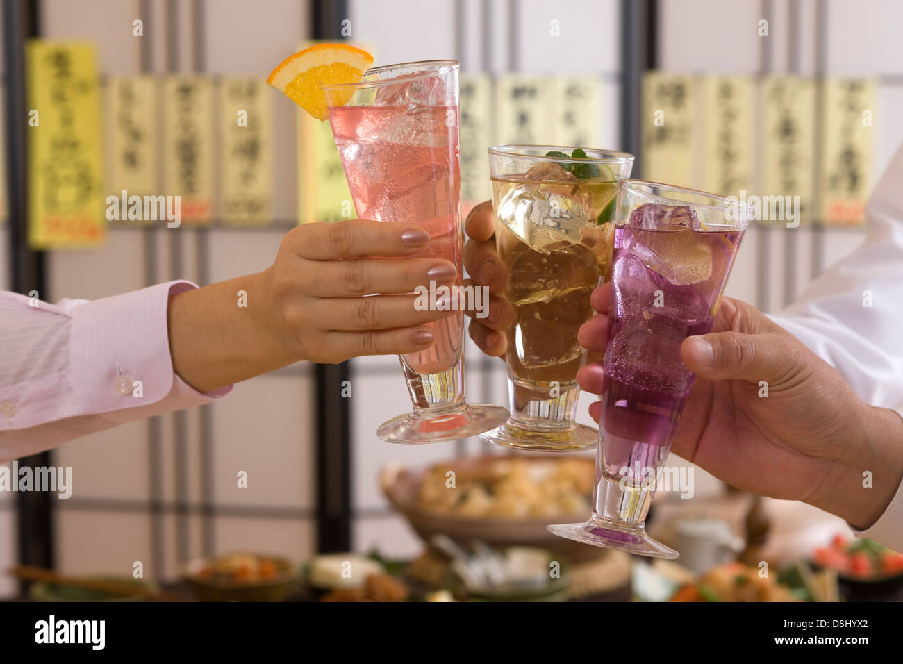 Tres personas brindando con varios cócteles en Izakaya Foto de stock