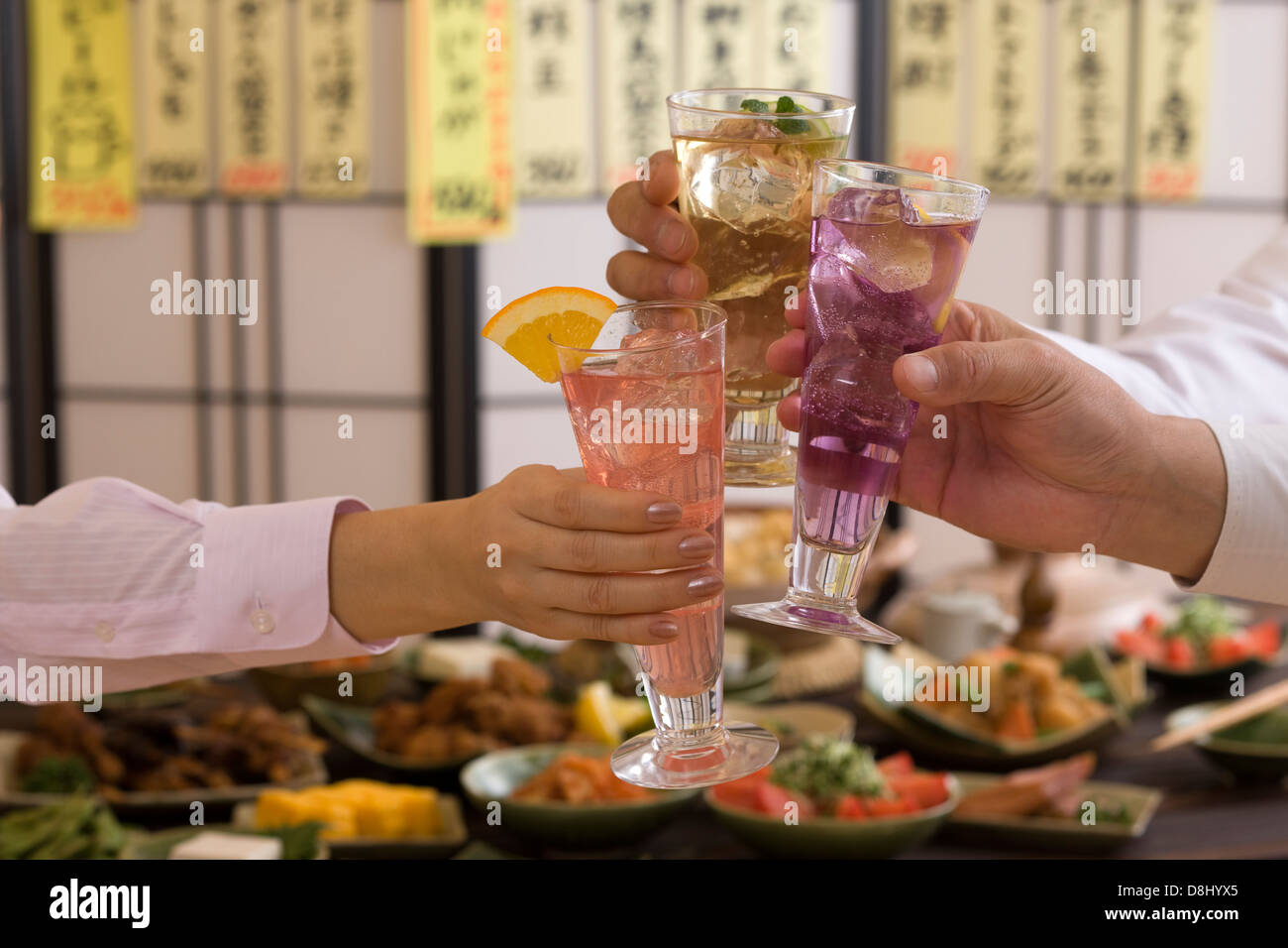 Tres personas brindando con varios cócteles en Izakaya Foto de stock